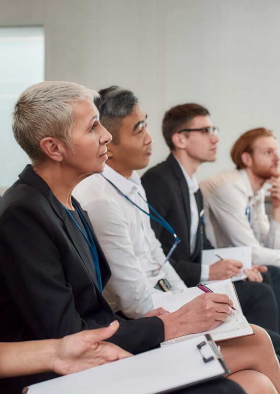 Multi-ethnic audience sitting in a row while listening to presentation at conference hall